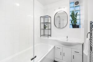 a white bathroom with a sink and a mirror at Stylish 2 bed Central London in London