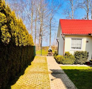 a house with a red roof and a brick driveway at Pokoje Nad Klifem in Trzęsacz