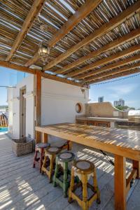 a wooden table and stools under a wooden pergola at Casa Stella - Authentic Luxury Rooftop Pool in Cartagena de Indias