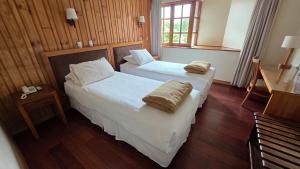 two beds in a hotel room with two towels on them at Hotel Casa Woerner - Caja los Andes in Valdivia
