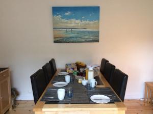 a dining room table with chairs and a painting on the wall at Seaways Cottage Hoylake in Hoylake