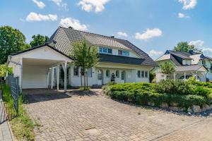 a large white house with a brick driveway at Ferienhaus "Stella Olivia" - Bade- & Saunawelt täglich inklusive in Lobbe