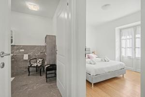 a white bedroom with a bed and a chair at Apartment Maira in Chiavenna
