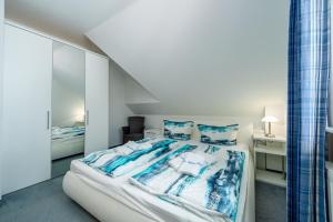 a bedroom with a bed with blue and white sheets at Ferienhaus "Stella Olivia" - Bade- & Saunawelt täglich inklusive in Lobbe