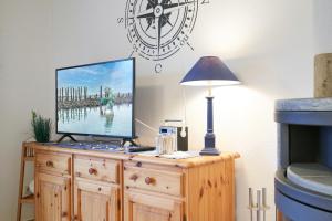 a tv on a wooden dresser with a lamp and a clock at Muschelsucher 2 in Nordstrand +14 photos