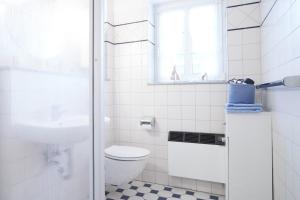 a white bathroom with a toilet and a window at Muschelsucher 2 in Nordstrand