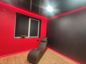 a red room with a chair in a room with a window at RED Тематичні Апартаменти in Zhytomyr +2 photos