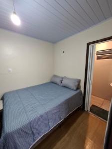 a bedroom with a bed with a blue comforter at Picco da Ilha Hostel in Florianópolis
