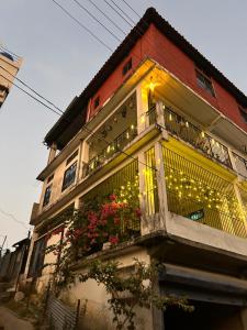 a building with a balcony with christmas lights on it at BeeHive Homestay in Hāflong