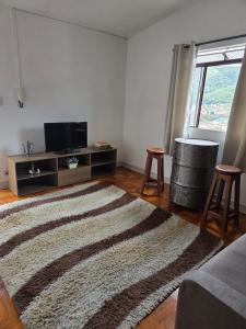a living room with a rug and a tv and stool at Casa confortável e central in Poços de Caldas