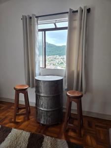 a room with a table and two stools and a window at Casa confortável e central in Poços de Caldas