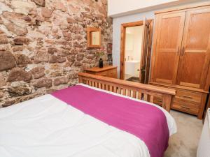 a bedroom with a bed and a stone wall at Cygnet Cottage in Berwick-Upon-Tweed