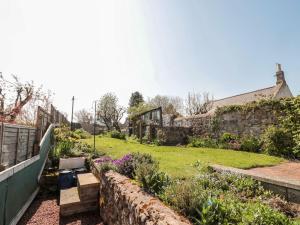 a garden with a stone wall and flowers at Cygnet Cottage in Berwick-Upon-Tweed