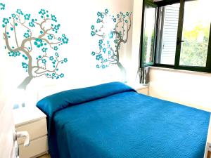 a bedroom with a bed with blue sheets and a tree mural at Casa Roccella in Buonfornello