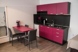 a small kitchen with red cabinets and a red table at Rooms Rebolj in Osijek