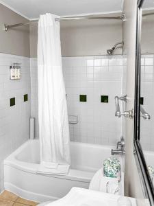 a white bathroom with a tub and a toilet at Courtesy Inn Downtown Eugene in Eugene