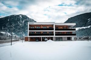 a building in the snow in front of mountains at Residence Louise in Vipiteno