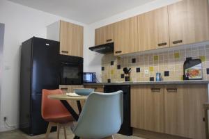 a kitchen with a table and a black refrigerator at Le nid des Huttes in Gravelines