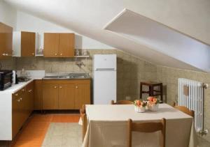 a kitchen with a table with chairs and a white refrigerator at B&B SANTA MARIA VALLEVERDE appartamento vicinissimo alla Clinica L'immacolata in Celano