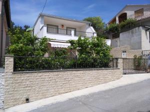 a brick wall with a fence in front of a building at Cesarica Studio near sea in Cesarica