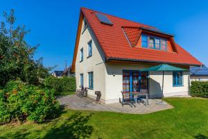 a house with an orange roof with a table and chairs at Ferienwohnung Katharina EG in Wohlenberg +11 photos