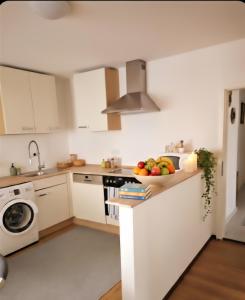 a white kitchen with a bowl of fruit on the counter at Ferienwohnung TALISA in Günzburg +15 photos