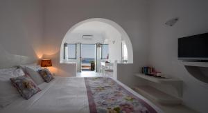 a bedroom with a large bed with an arched window at Anastasis Apartments and Spa in Imerovigli +98 photos