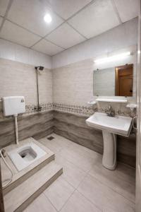 a bathroom with a toilet and a sink and a mirror at Hotel Noor Sky in Islamabad