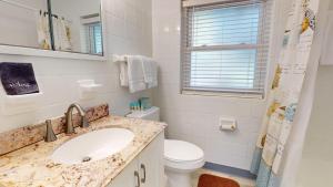 a white bathroom with a sink and a toilet at Atlantic Breeze #7 in Jekyll Island +10 photos