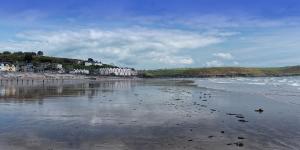 
a beach with a body of water and a lighthouse at The Old Imperial Hotel Youghal in Youghal
