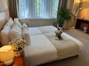 a bedroom with a large white bed with a table at Plaza Hotel Gyula in Gyula