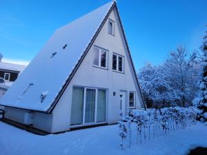 a white house with a gambrel roof in the snow at Ferienhaus ROSA mit Sauna in Dorum-Neufeld