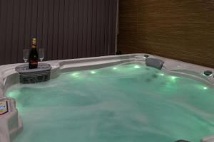 a hot tub with a bottle of wine and two glasses at Gîte l'évasion in Chaillac-sur-Vienne +4 photos