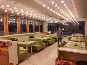 a man standing in a dining room with tables and chairs at Hotel Valley in Akteshwar +14 photos