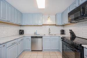a white kitchen with blue cabinets and a dishwasher at Phoenix X 504 in Orange Beach