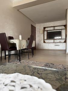 a dining room with a table and chairs and a tv at Appartement moderne - Résidence privée in Kenitra