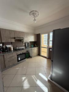 a large kitchen with stainless steel appliances and a tile floor at Appartement moderne - Résidence privée in Kenitra