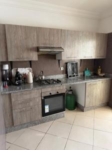 a kitchen with wooden cabinets and a counter top at Appartement moderne - Résidence privée in Kenitra