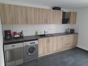 a kitchen with a washing machine and wooden cabinets at Boardinghaus Waldesruh in Lohne