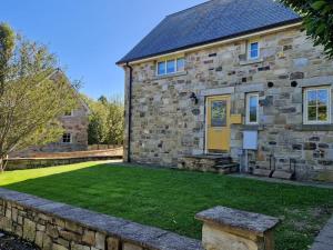 a stone house with a yellow door and a yard at 2 Bed in Chathill oc-77990 in Ellingham