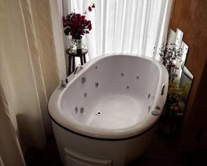 a white bath tub in a bathroom with a window at Espaço Casa da Árvore - 3 opções de chalés in Ouro Preto