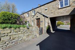a brick building with a garage and a stone wall at 3 Bed in Leyburn oc-ds013 in West Witton