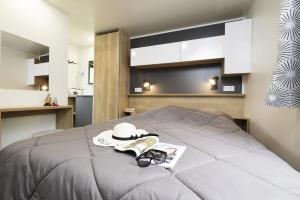 a bedroom with a bed with a hat and glasses at ZEcamping 4 étoiles animaux acceptés piscine couverte in Loupiac