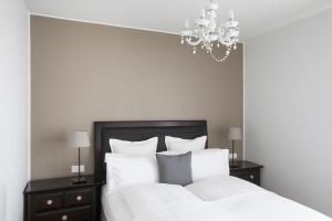 a bedroom with a bed with white sheets and a chandelier at Ódinsvé Hotel Apartments in Reykjavík +23 photos