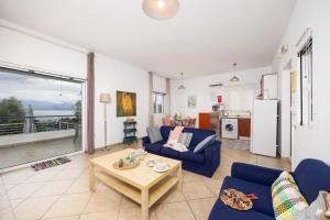 a living room with a blue couch and a table at Villa Calliope Kalamaki in Kalamaki