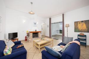 a living room with two blue couches and a fireplace at Villa Calliope Kalamaki in Kalamaki
