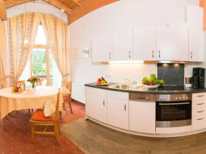 eine Küche mit weißen Schränken und einem Tisch im Zimmer in der Unterkunft Gästehaus Büchele in Hirschegg