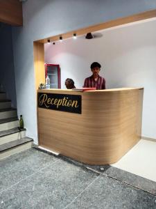 a man is standing behind a reception desk at Hotel Nidhivan Palace in Surat