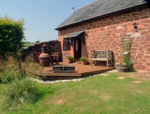 a brick house with a wooden deck with a bench at 2 Bed in Exminster oc-h28725 in Exminster +4 photos
