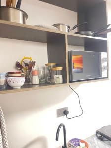a kitchen shelf with a microwave and a sink at Naisolas place in Marimbeti